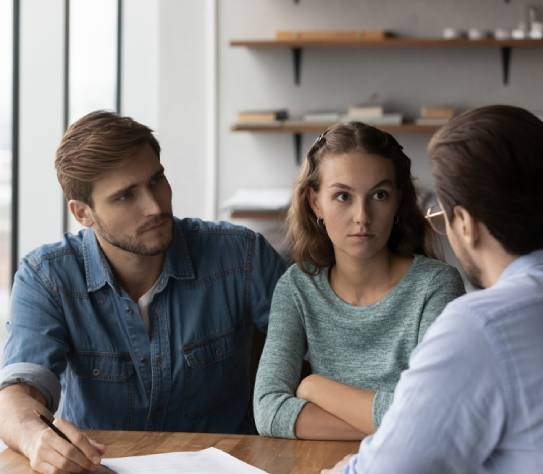 young Caucasian couple buyers talk with male realtor or real estate agent dissatisfied with contract terms regulations