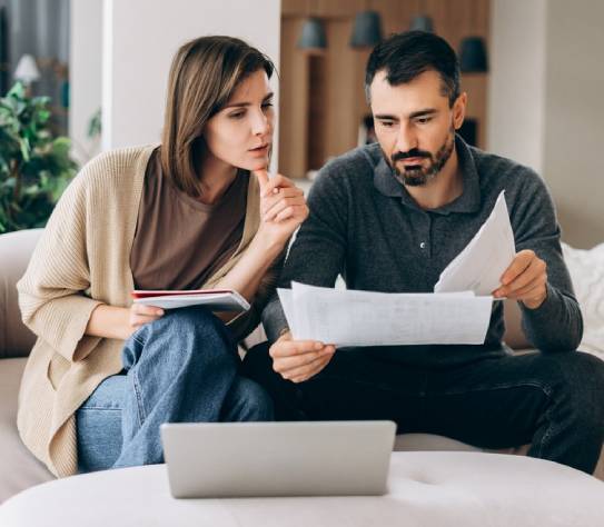 Couple reviewing bills and documents, making financial planning decisions at home